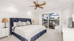 Ein Schlafzimmer mit einem großen Bett, zwei Nachttischen, einem Schreibtisch und einem Deckenventilator.