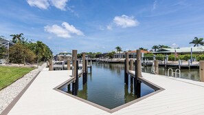 Un port de plaisance avec des bateaux amarrés, un ciel dégagé et une zone riveraine bien entretenue.