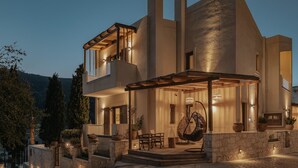 A modern two-story house with a balcony, outdoor seating, and a hanging chair. - Manili Suites & Villas, an SLH Hotel (Archanes-Asterousia)