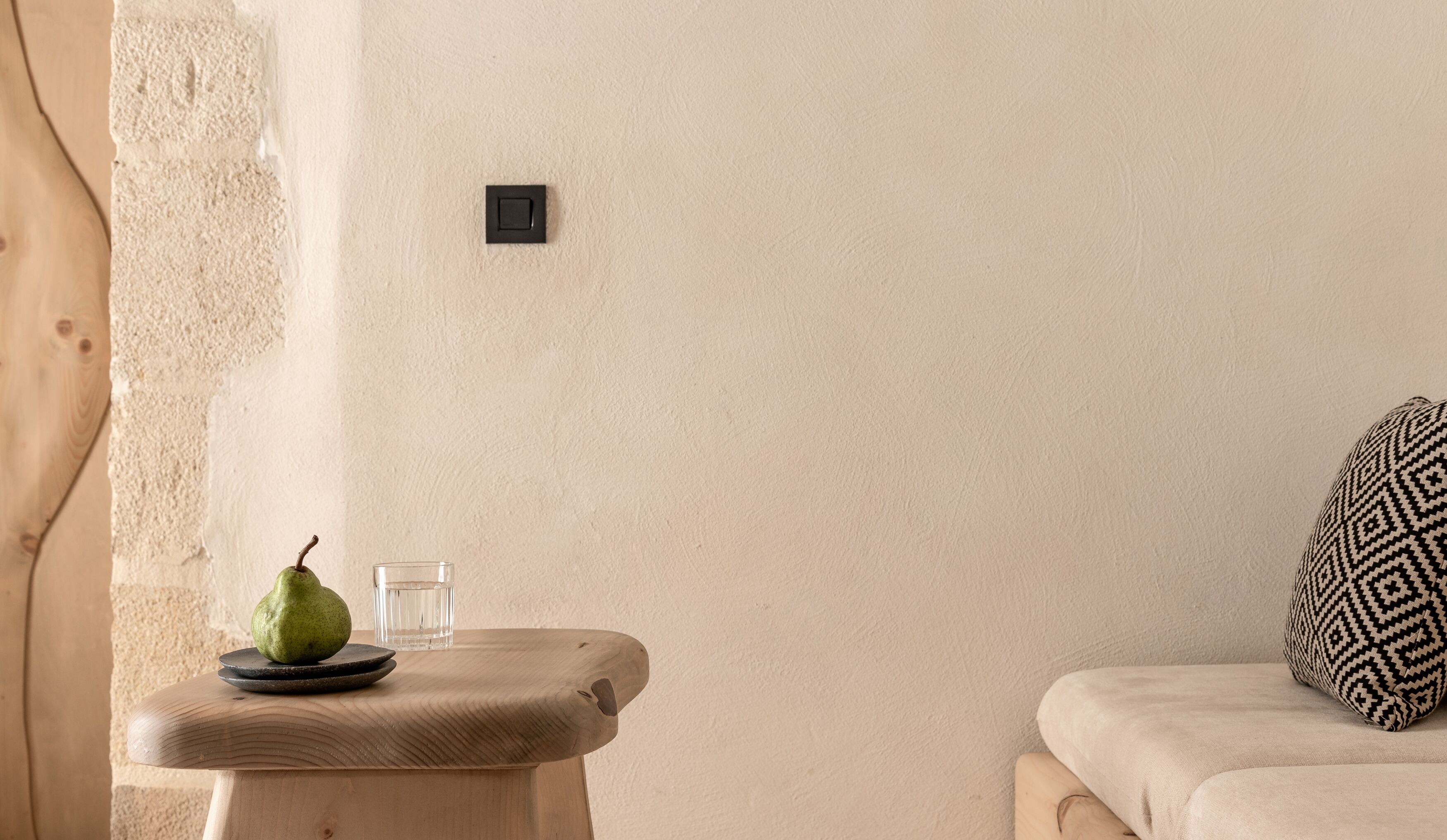 Quarto minimalista com uma mesa de madeira, um copo de água e uma pera.