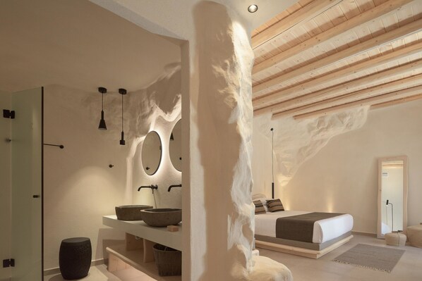 Une chambre moderne avec un grand lit, un lavabo intégré et un miroir.