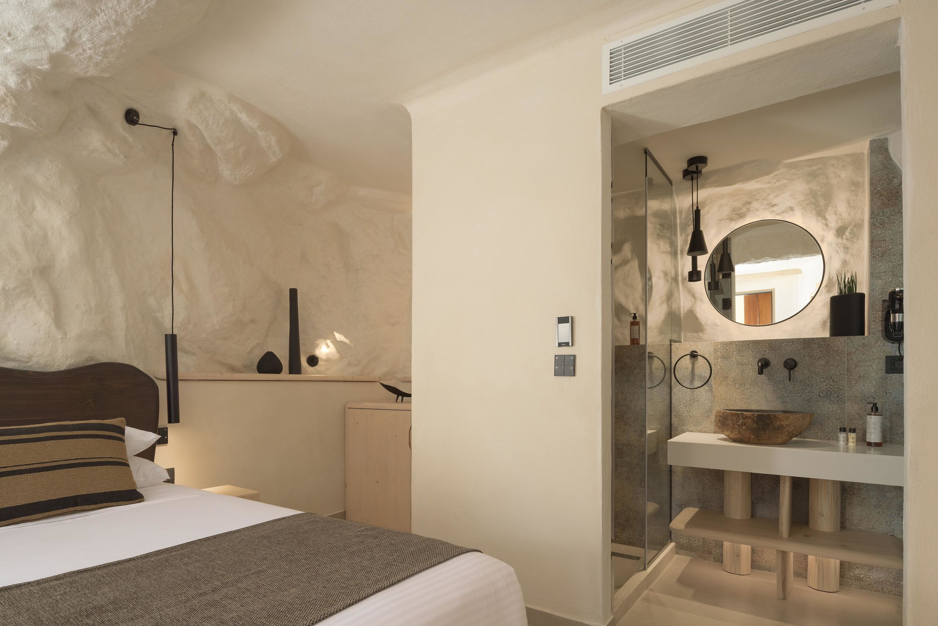 A bedroom with a bed, bedside lamp, and a nightstand.