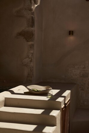 A stone wall with a small light fixture and a bowl with green vegetables on a ledge. - Manili Suites & Villas, an SLH Hotel (Archanes-Asterousia)