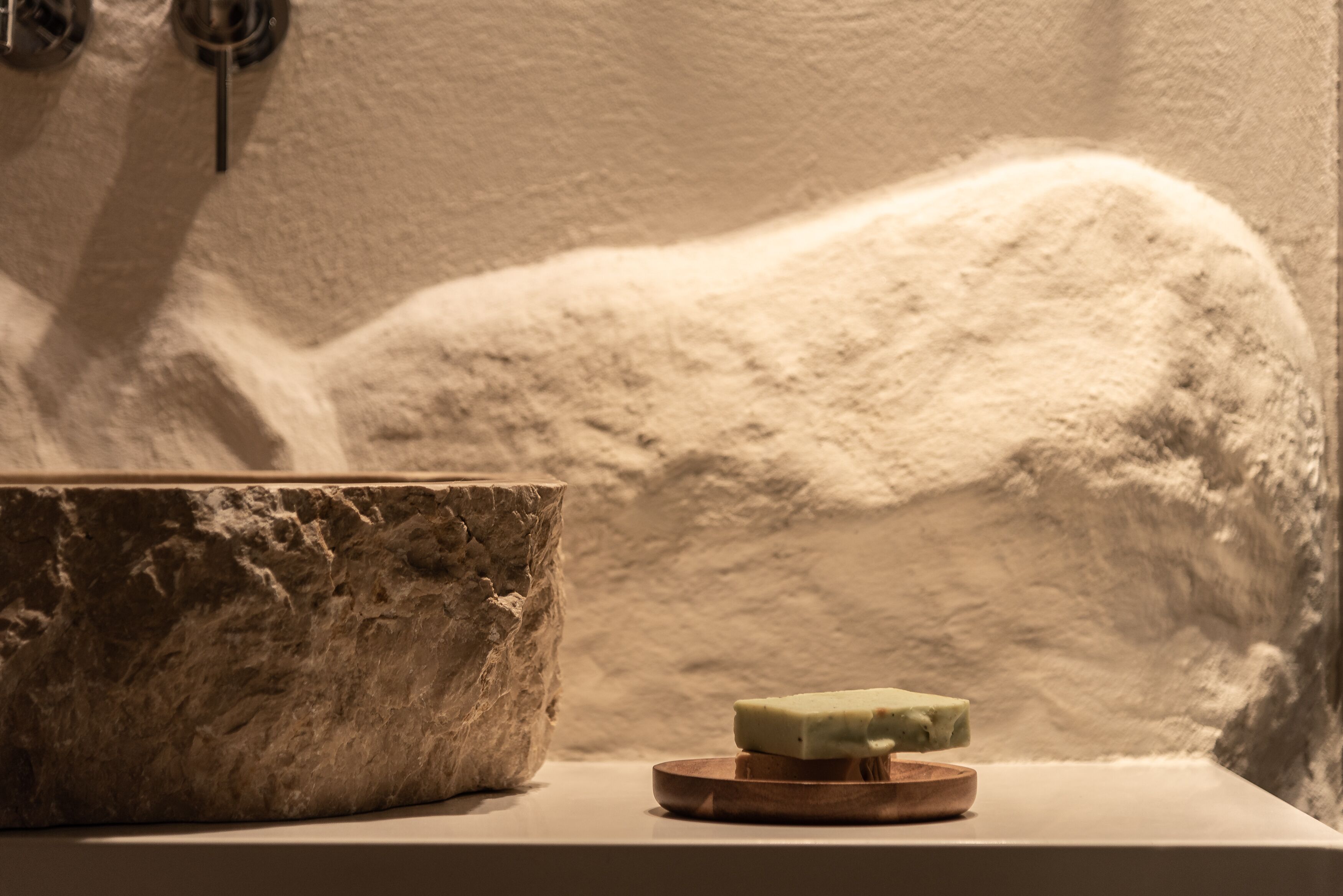A stone basin with a bar of soap on a wooden tray.