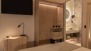 Una camera da letto moderna con un letto, una TV, un armadio in legno, una toeletta con specchio e un piccolo ripiano con articoli da toilette.