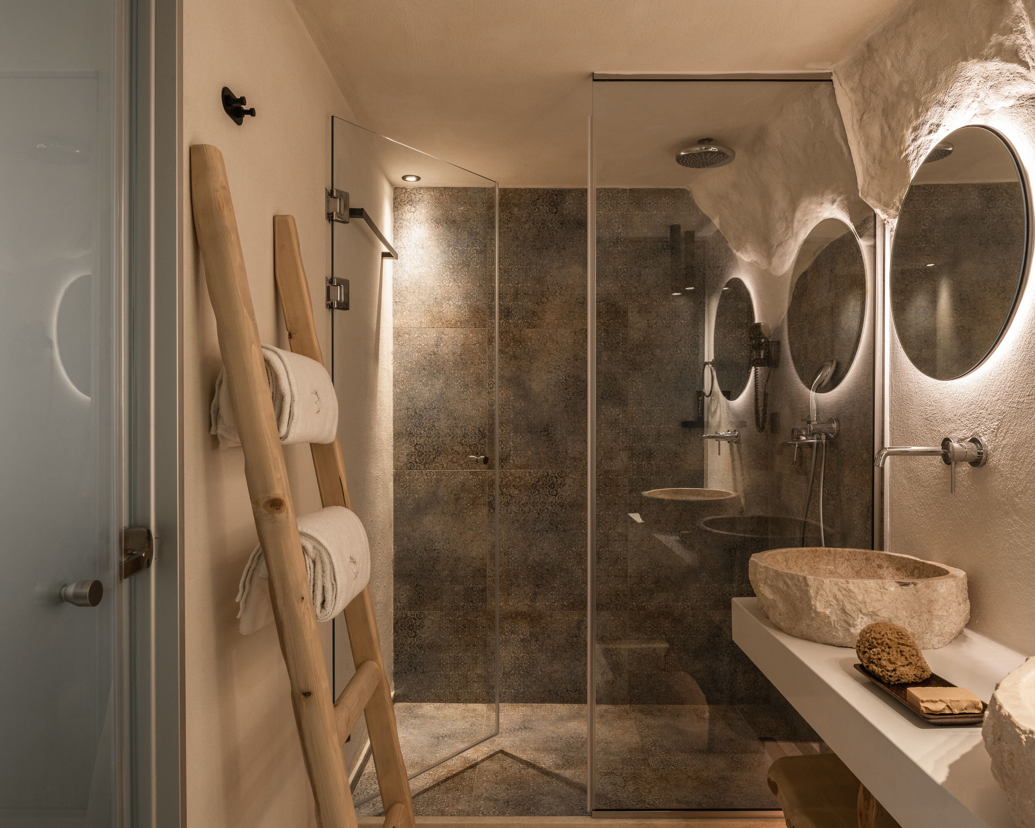 Un bagno moderno con cabina doccia in vetro, una scala in legno e uno specchio grande.