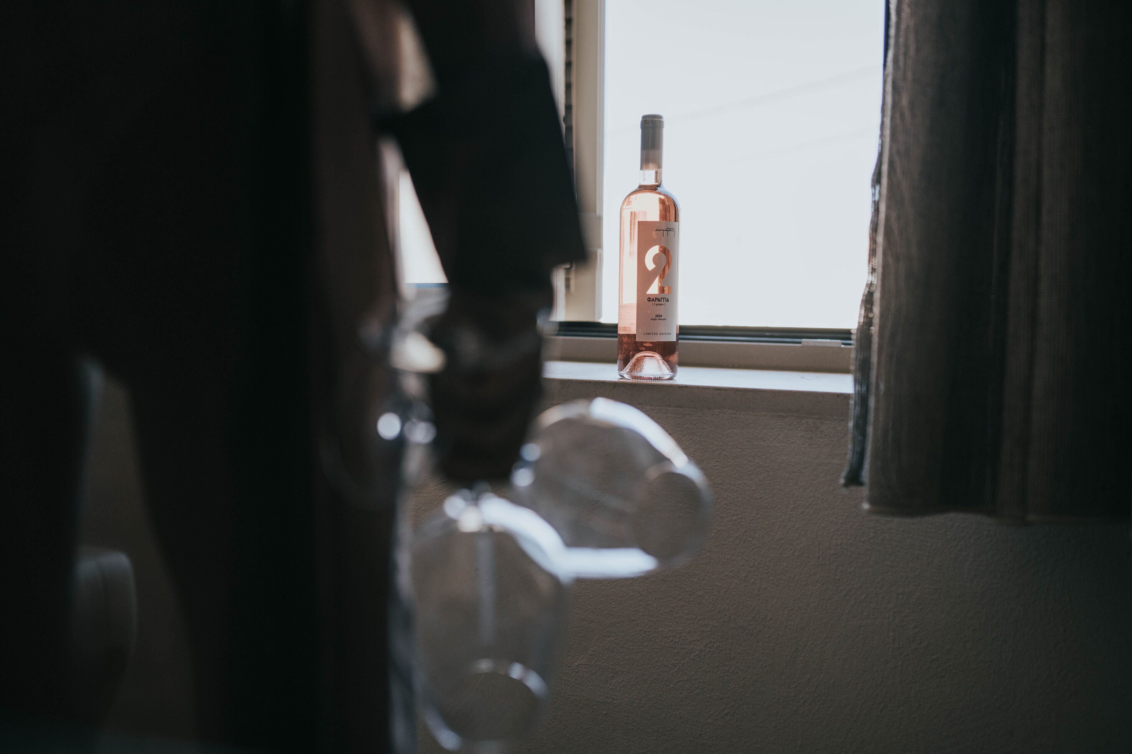 A bottle of liquor on a windowsill with a view of the sky.