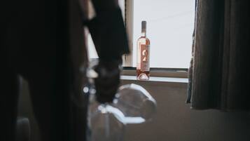 A bottle of liquor on a windowsill with a view of the sky.