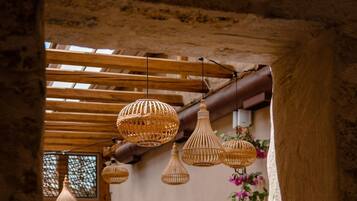 An interior with rustic wooden beams, wicker pendant lights, and a stone wall.