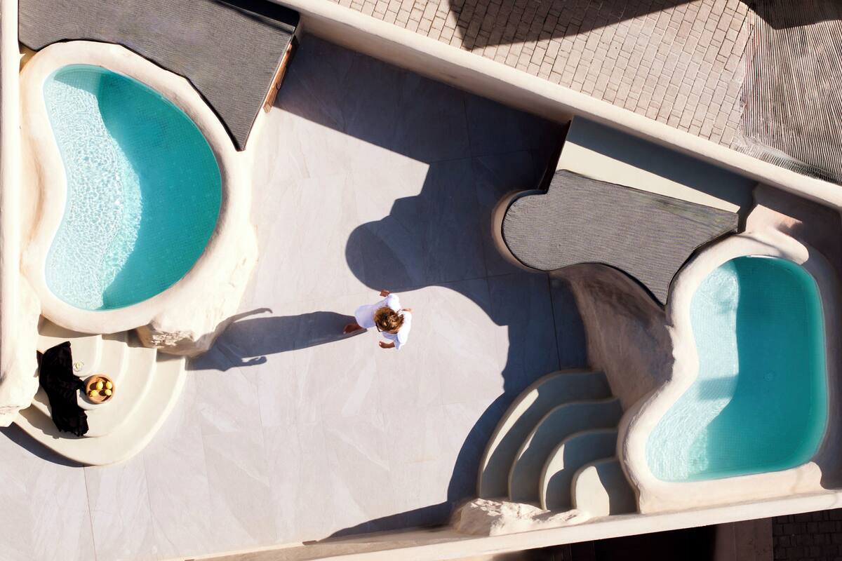 A pool area with two separate pools and a lounge chair.