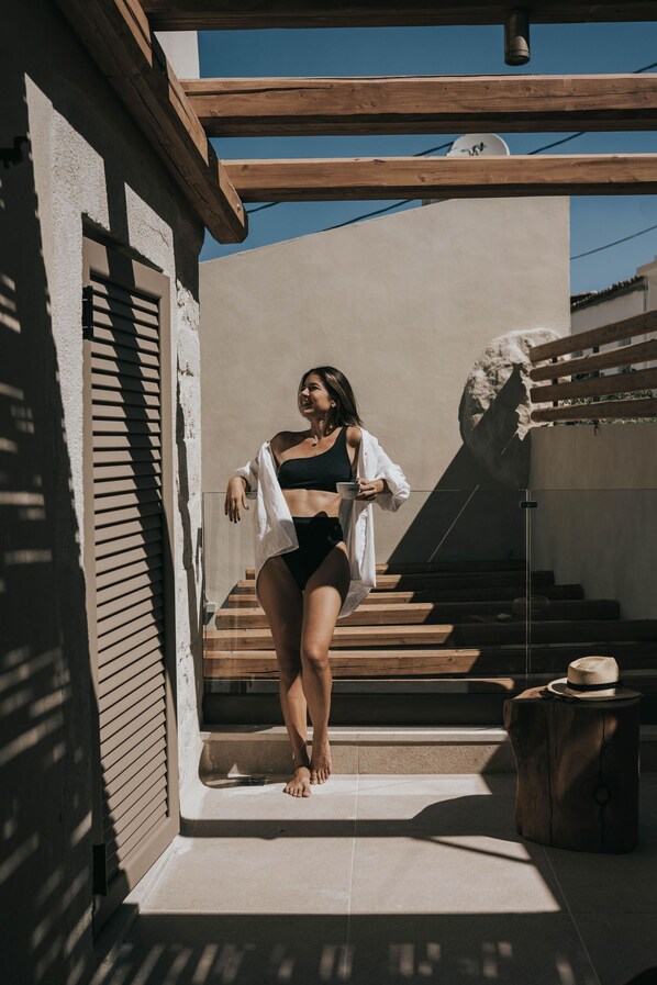 A person standing on a staircase in a modern building with a wooden beam structure and a satellite dish. - Manili Suites & Villas, an SLH Hotel (Archanes-Asterousia)
