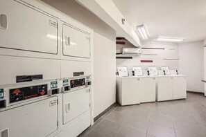A laundry facility with multiple washing machines and dryers, a control panel, and a tiled floor. - Central quaint 1BR close to UT, Moody Center, & DT (Austin)