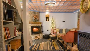 A cozy living room with a fireplace, a sofa, a coffee table, and a bookshelf filled with books. - Dandy Villas Metsovo-Metska-Down Town-Up to 7
 (Metsovo)