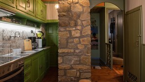 A kitchen with green cabinets, a stone pillar, and a wooden floor. - Dandy Villas Metsovo-Metska-Down Town-Up to 7
 (Metsovo)