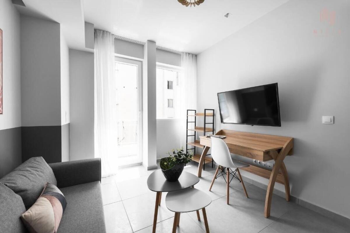 Ein modernes Wohnzimmer mit einer Couch, einem Couchtisch, einem Fernseher und einem Schreibtisch mit Stuhl.