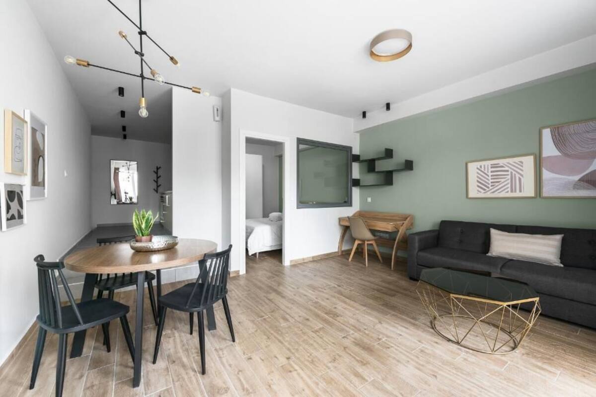 Una sala moderna con comedor, sofá y mesa de centro. Hay una planta en la mesa del comedor y obras de arte en las paredes.