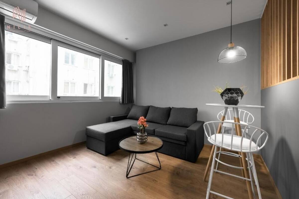 Ein modernes Wohnzimmer mit einer Eckcouch, einem runden Couchtisch und einem weißen Sessel.
