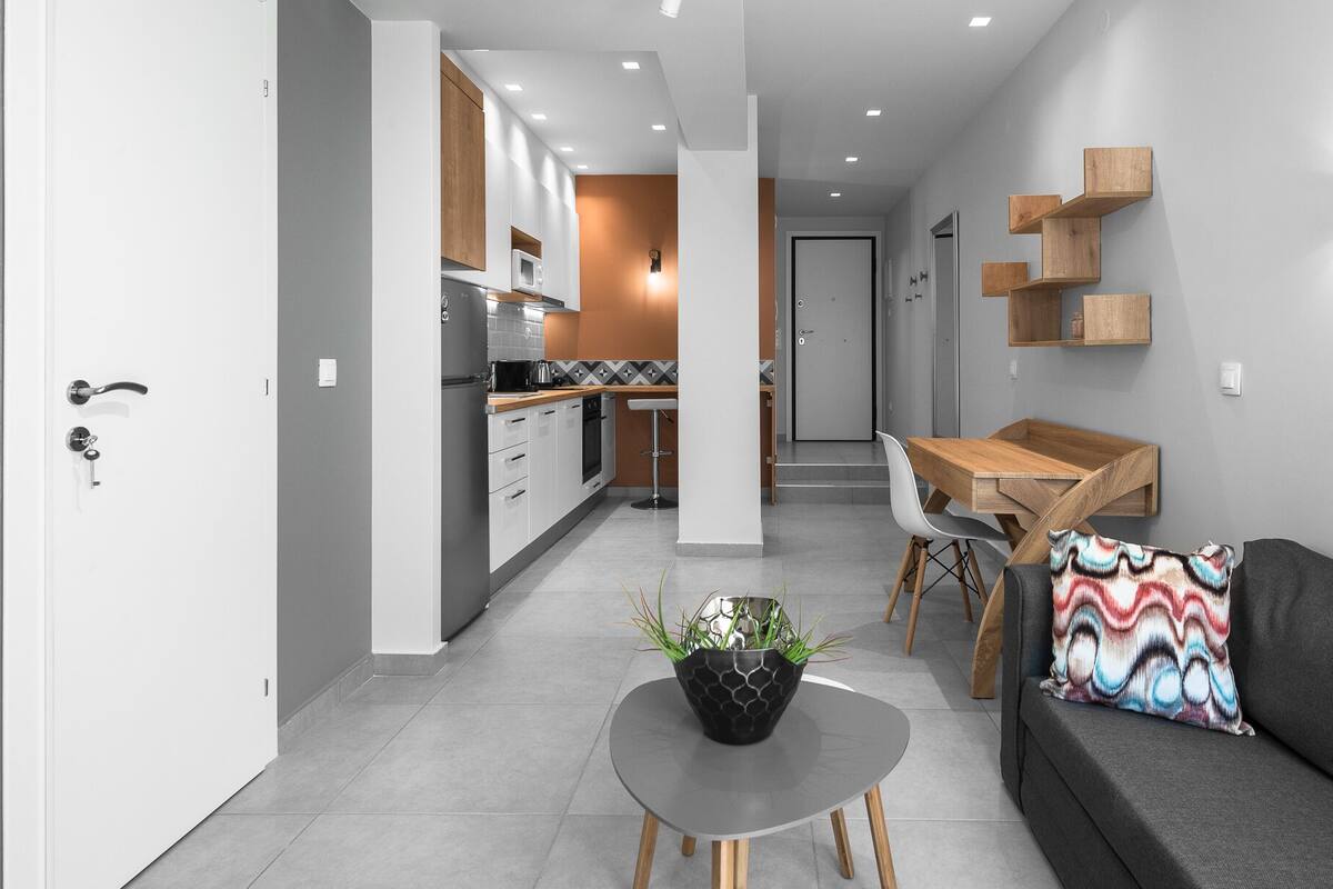 Una sala de estar moderna con un sofá gris, una mesa de centro con una planta y una mesa de comedor de madera.