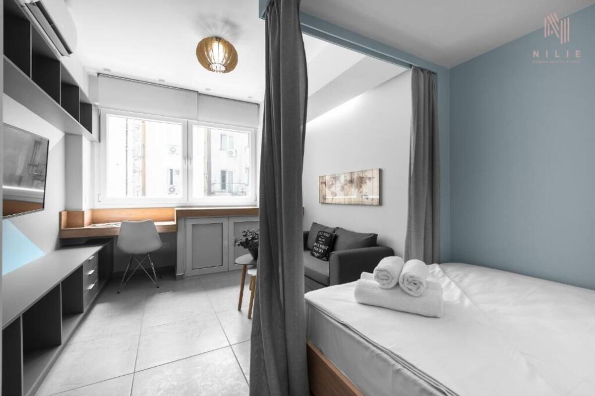 Ein modernes Hotelzimmer mit einem Bett, einem Schreibtisch, einem Stuhl, einem kleinen Tisch und einem Fenster.