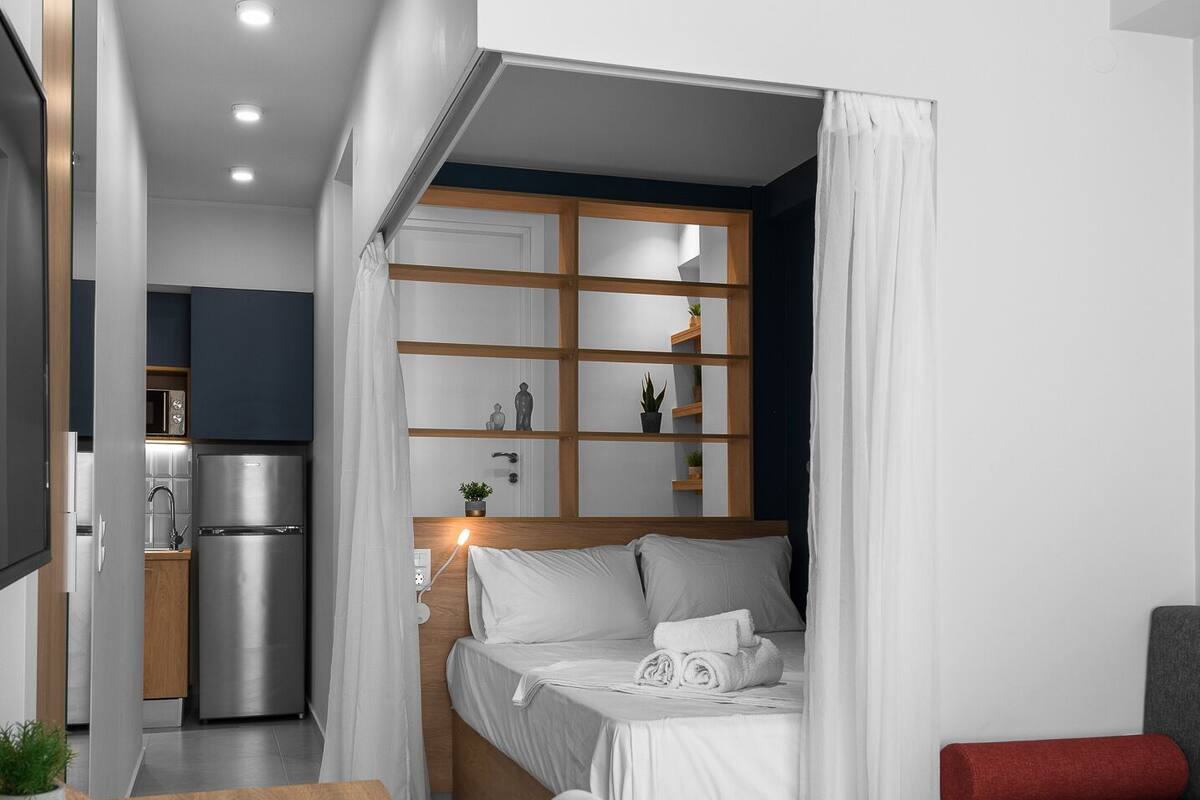 Ein kleines Schlafzimmer mit Bett, Nachttisch und einer Kochnische.