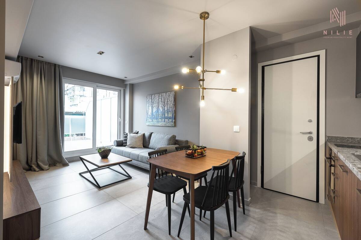 Una sala de estar moderna con comedor, ventanas grandes y vista a la ciudad.