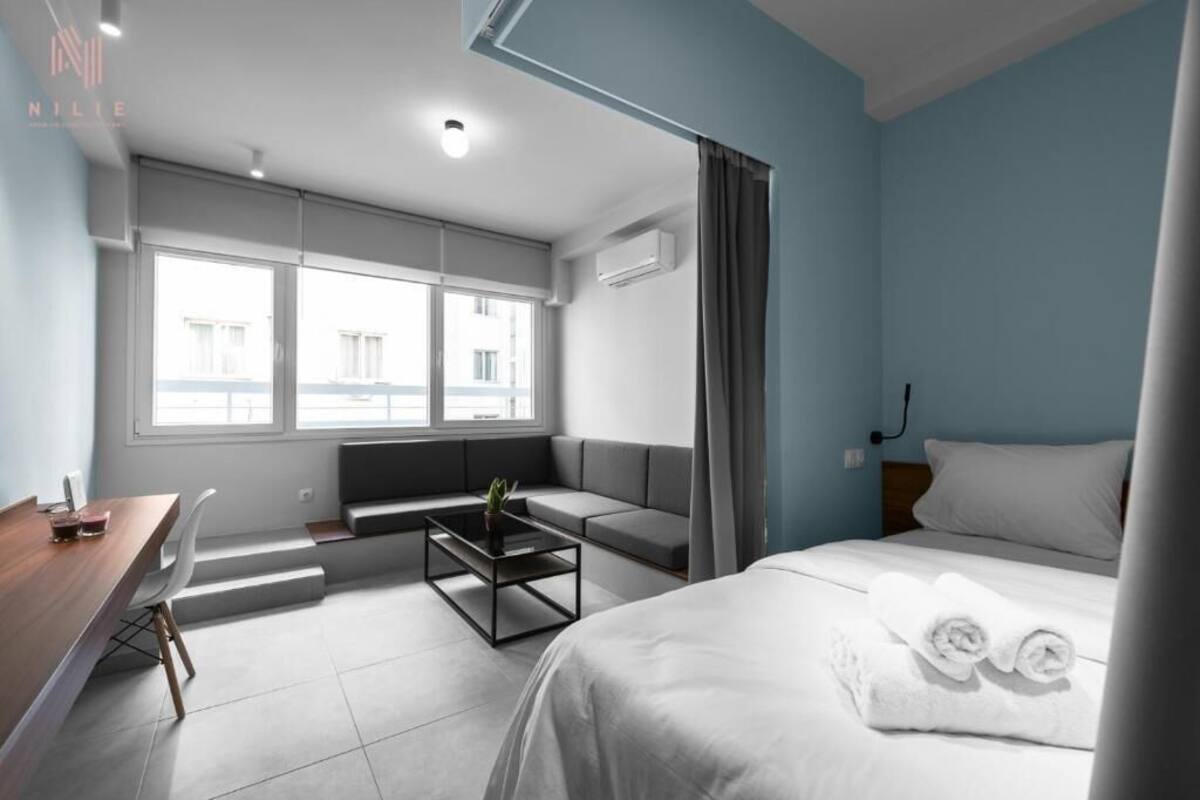 Ein modernes Hotelzimmer mit Bett, Schreibtisch, einer Couch und einem Fenster mit Vorhängen.
