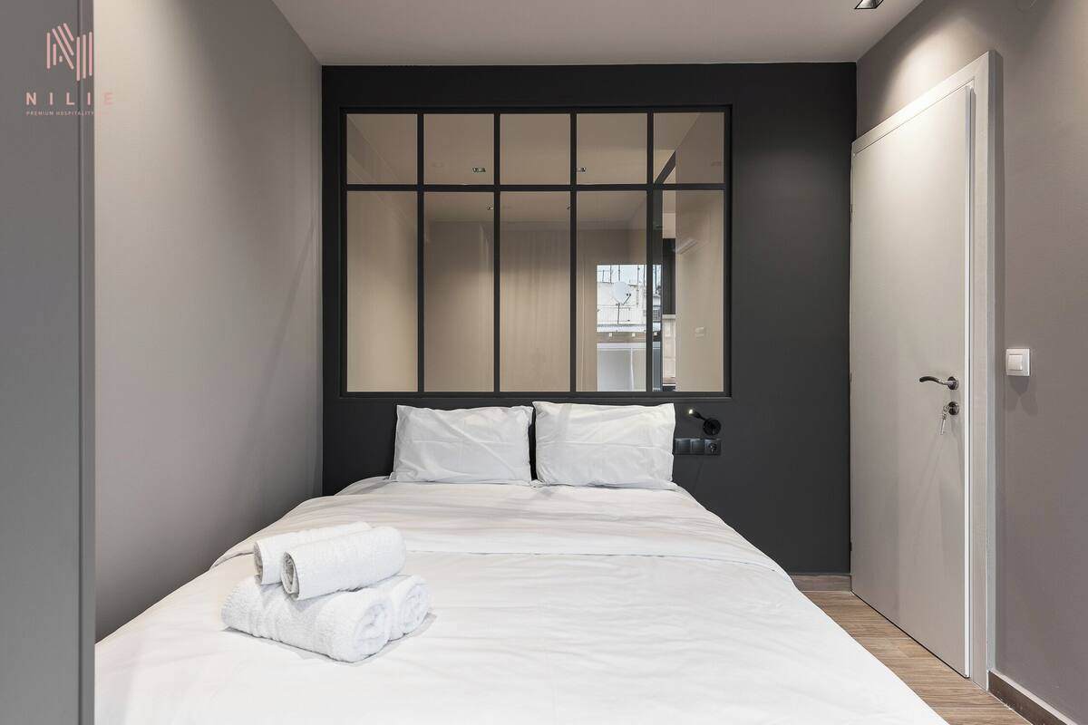 Una habitación de hotel moderna con una cama grande, un espejo y un armario.