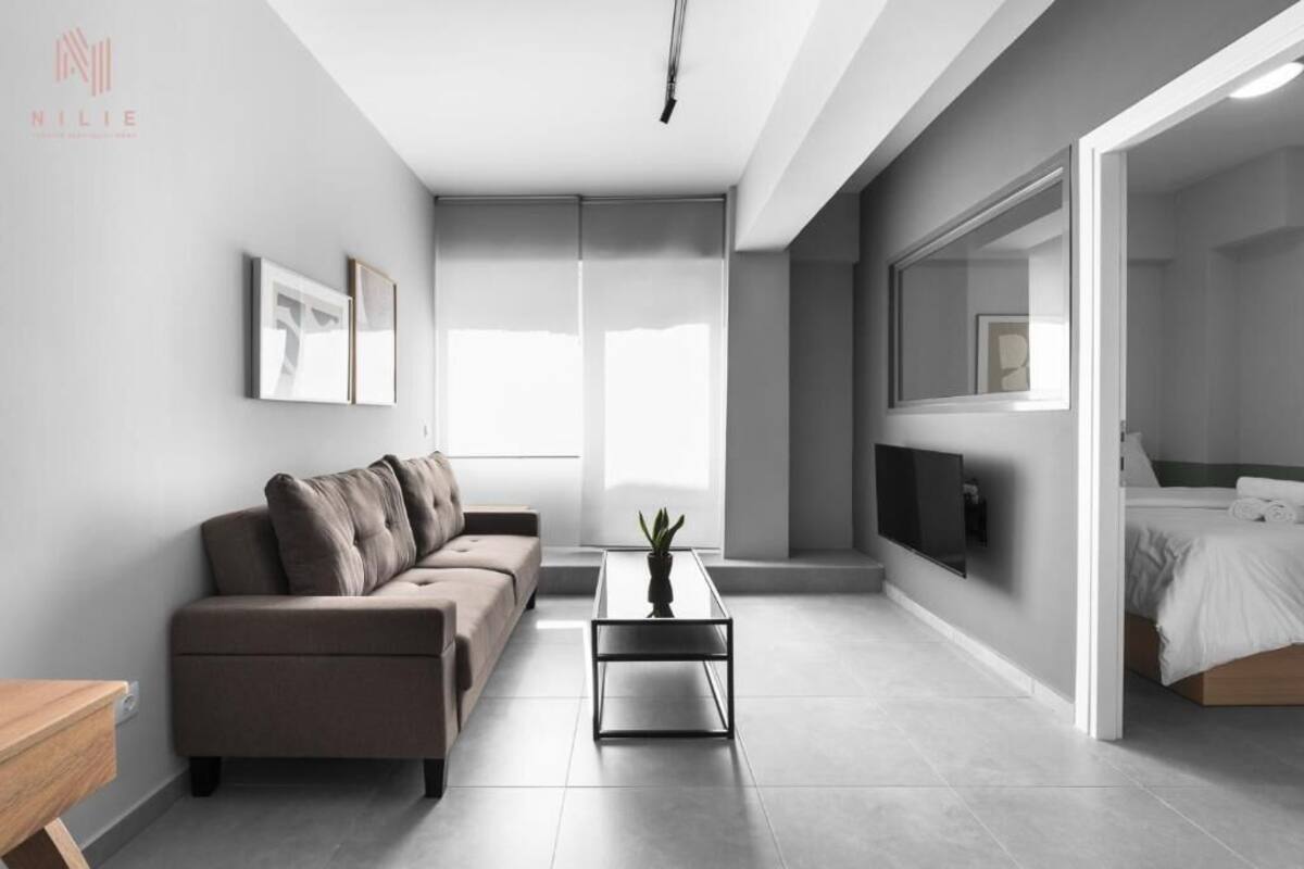 Una sala de estar moderna y minimalista con un sofá, una mesita de centro y una cama.