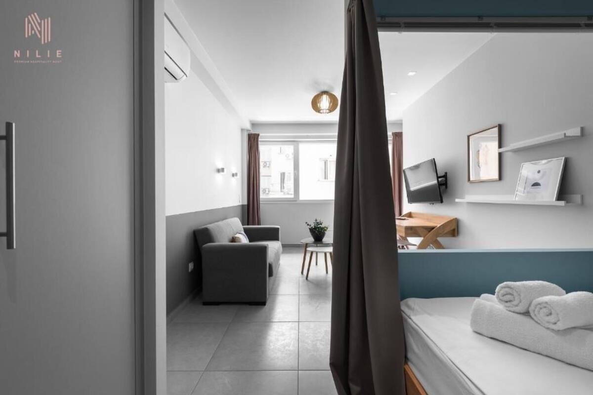 Ein modernes Hotelzimmer mit einem Bett, einer Couch, einem kleinen Tisch und einem Fernseher auf einem Schrank.