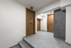 Un pasillo moderno con puertas de madera y suelo de baldosas grises.