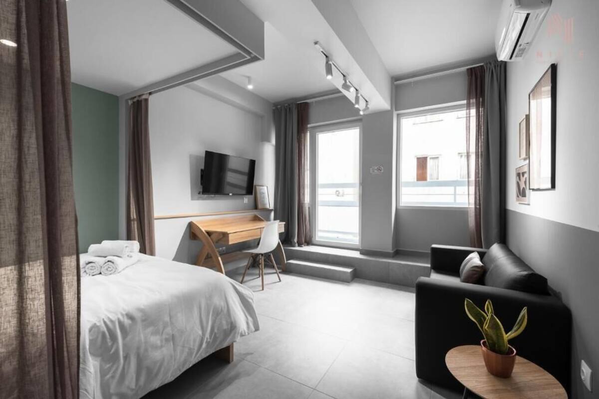 Ein modernes Hotelzimmer mit Bett, Schreibtisch, Sofa und Fernseher.