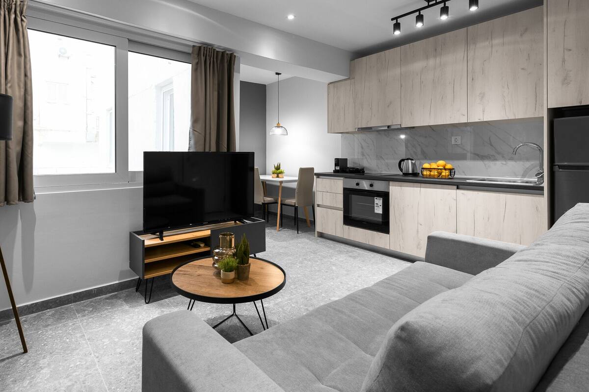 Una sala de estar moderna con un sofá, una mesa de centro, un televisor y una lámpara de pie.