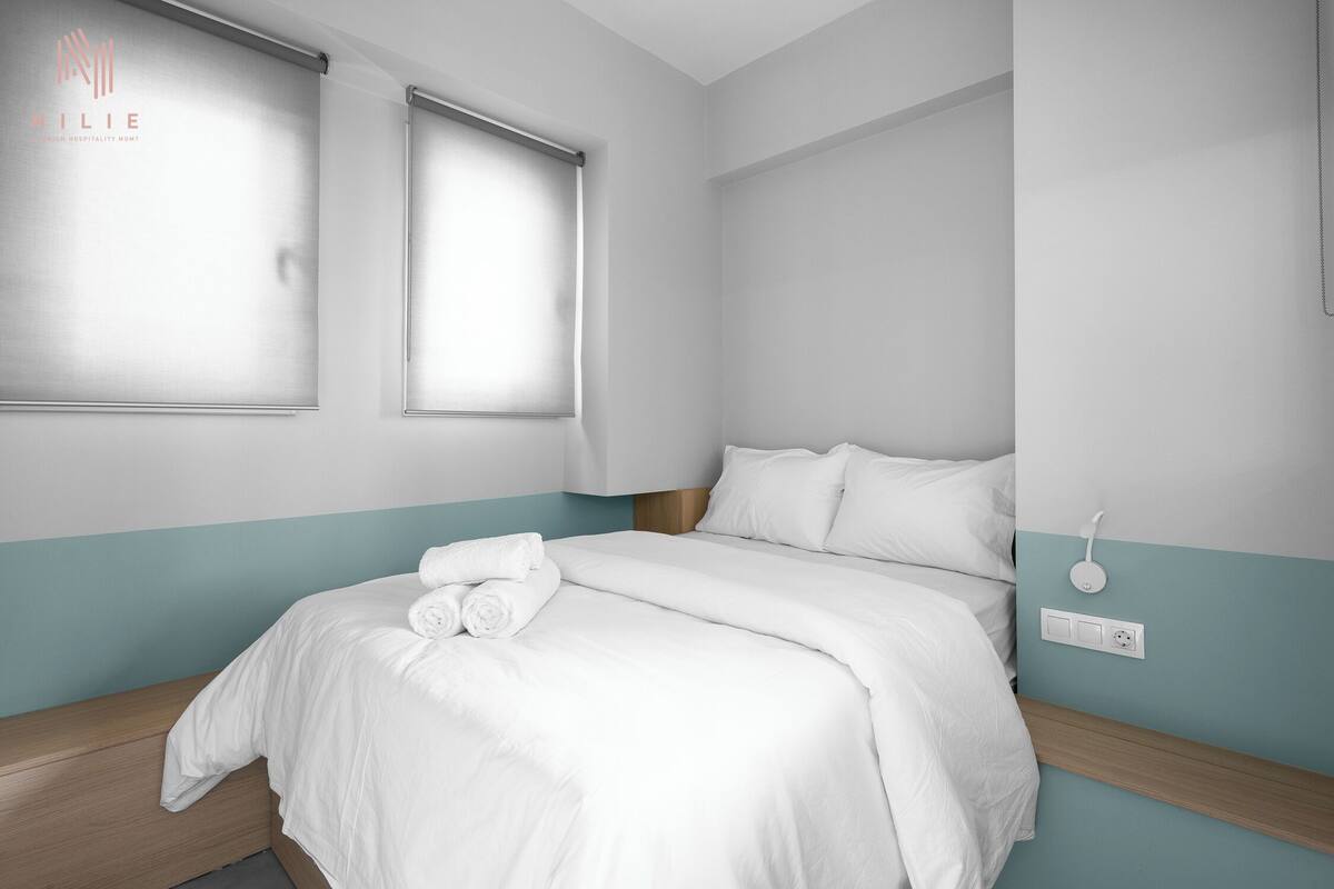 Una habitación de hotel con una cama, una ventana y un interruptor de luz en la pared.