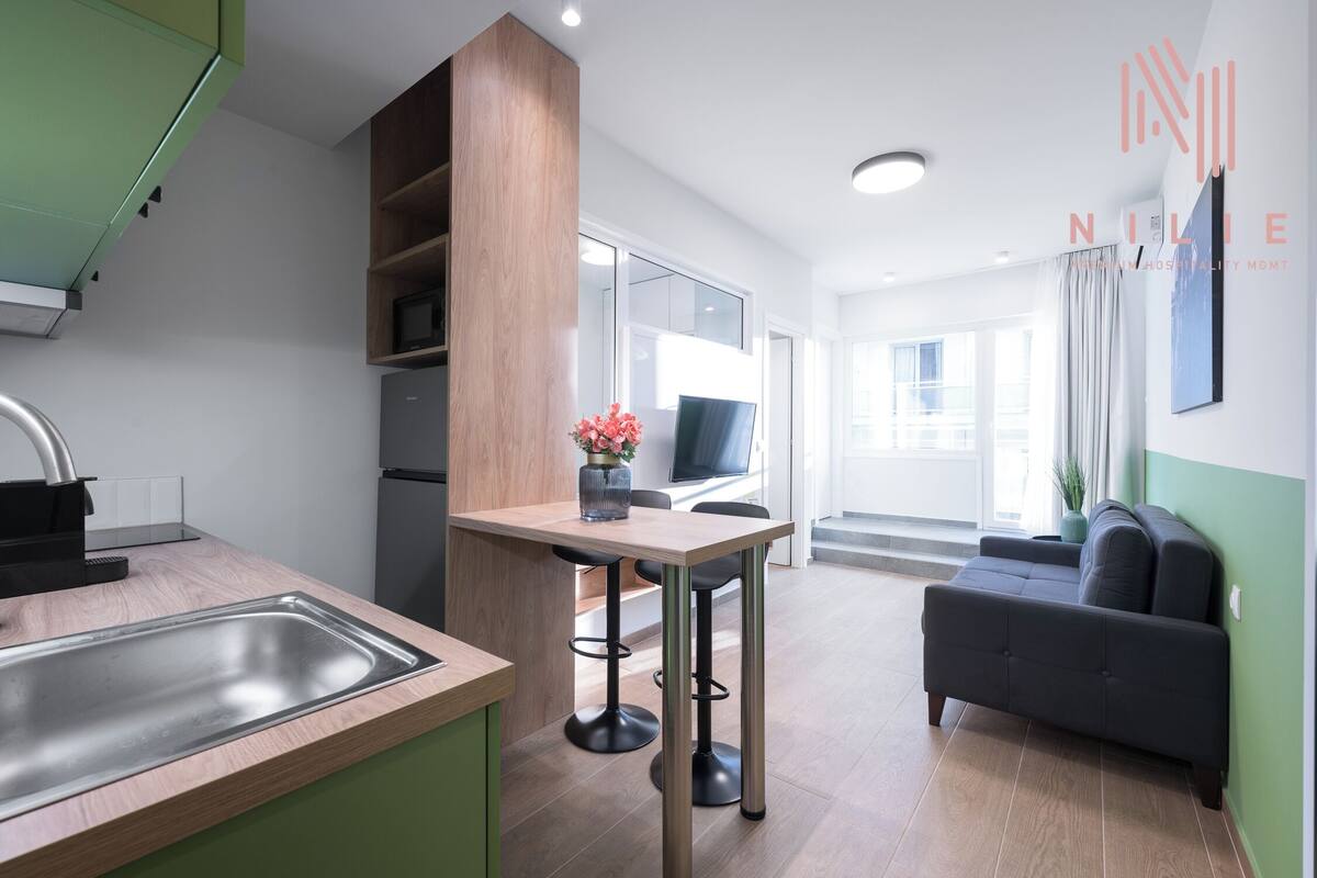 Una cocina moderna con un lavamanos integrado, una zona de comedor con una mesa y sillas, y un sofá en la sala de estar.