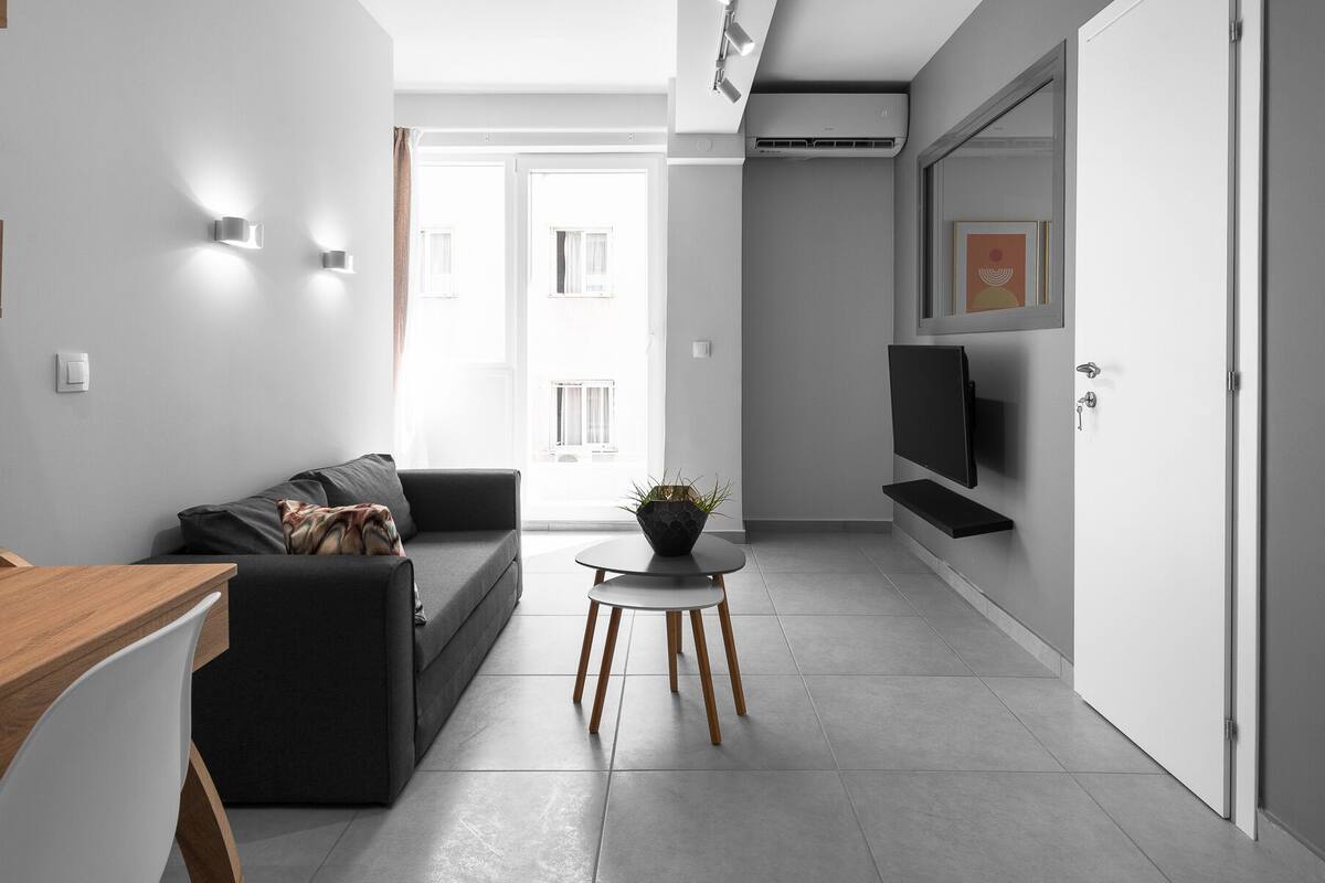 Una sala de estar moderna con un sofá, una mesa de centro y un televisor montado en la pared.