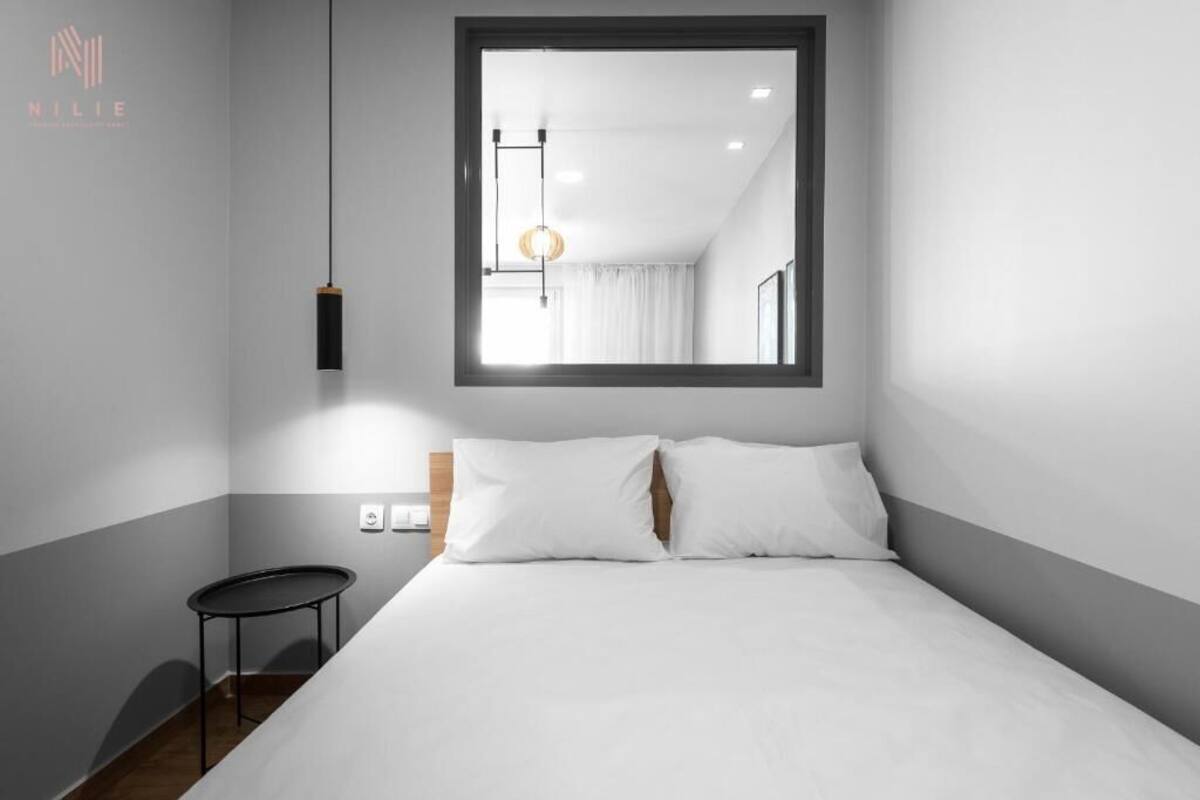 Un dormitorio moderno con una cama grande, una mesita redonda pequeña y una lámpara colgante.