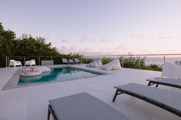 A rooftop pool area with lounge chairs, a small inflatable pool, and bean bags.