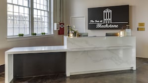 Un comptoir d’accueil au design en marbre, une grande fenêtre avec stores et une enseigne fixée au mur portant l’inscription « The Inn at Blackstone ».