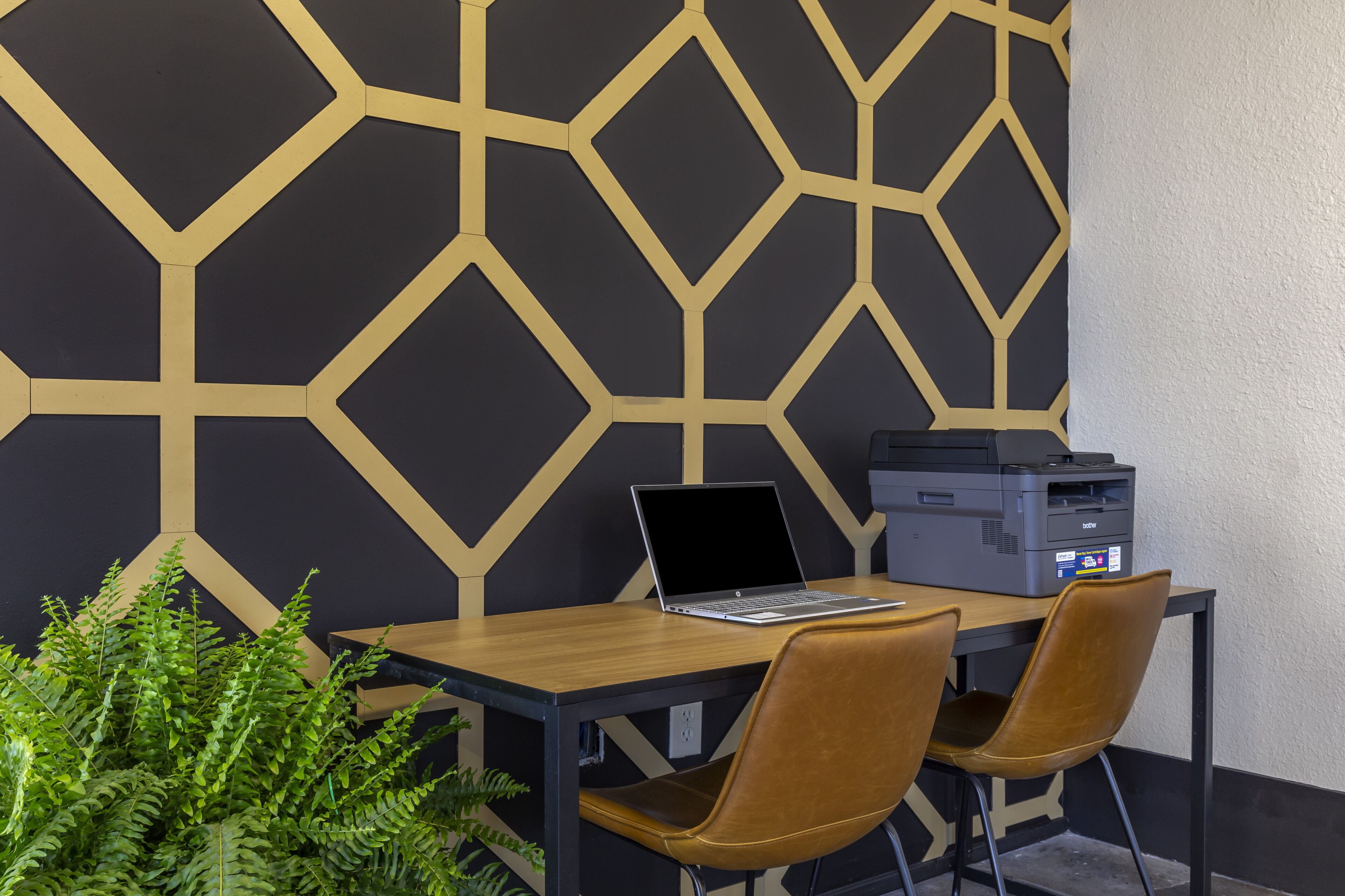 A workspace with a laptop, printer, and two chairs.