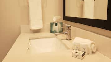 A bathroom with a white sink, a mirror, a towel rack, and Dove toiletries.