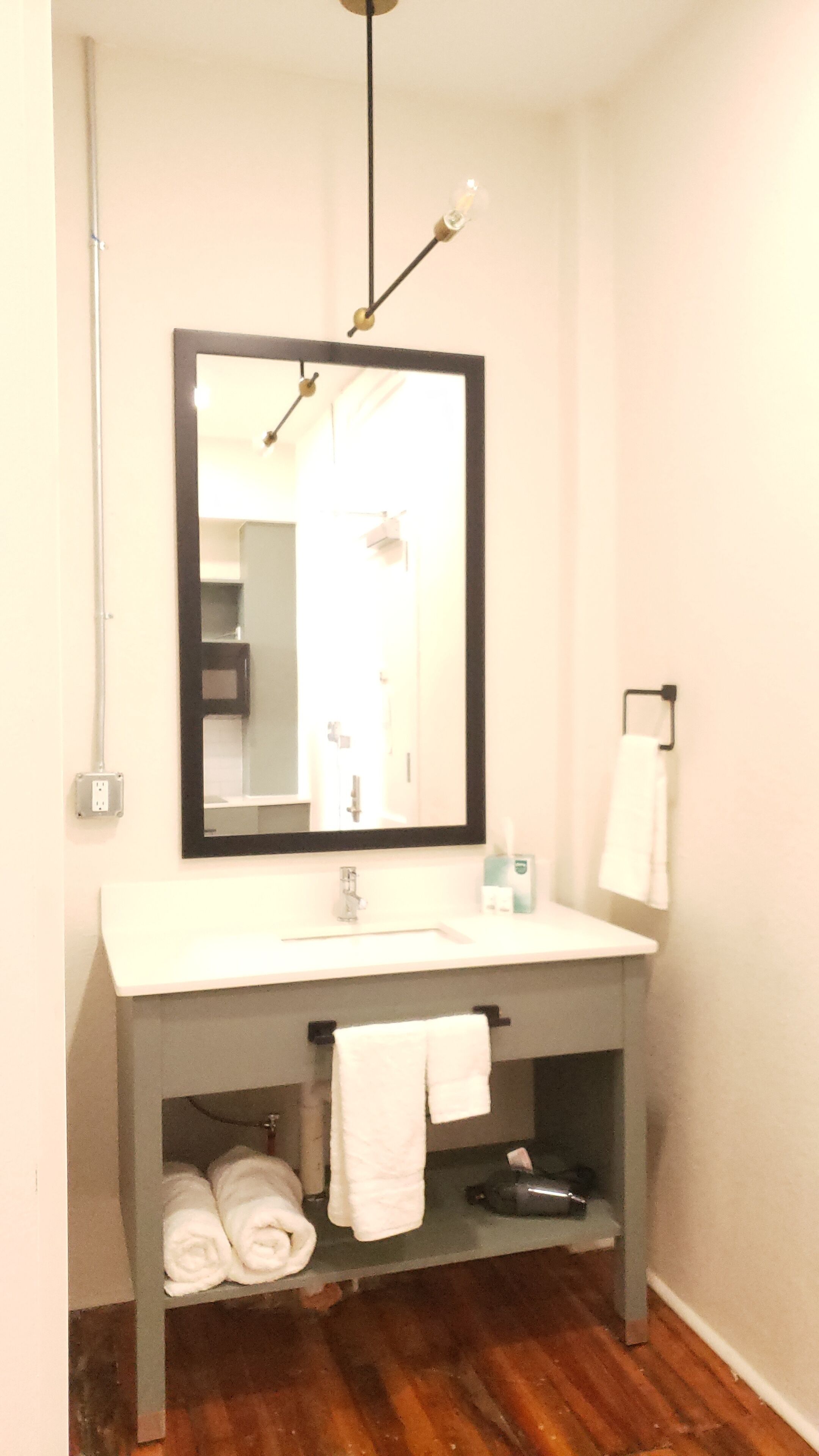 A bathroom with a white sink, a mirror, a towel rack, and a shelf with towels.