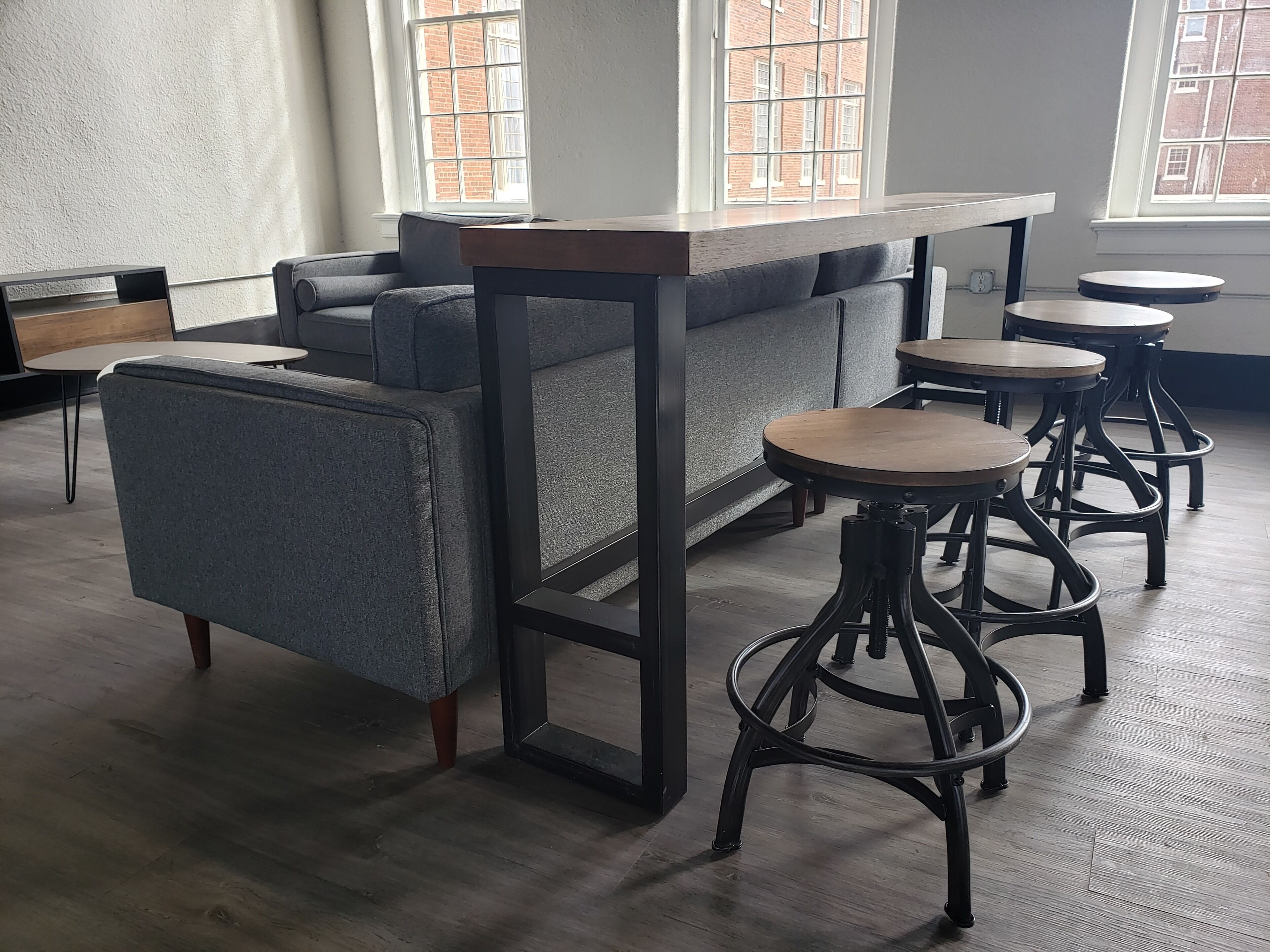 A modern interior with a sofa, a bar table, and bar stools.