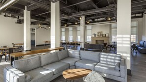 Un salon spacieux et moderne, doté d’un grand canapé d’angle gris, d’une table basse en bois et d’une table d’appoint en marbre.