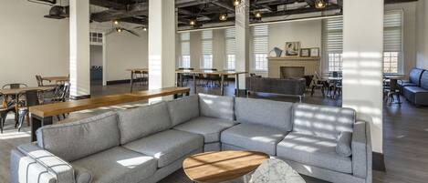 A spacious, modern lounge area with a large grey sectional sofa, a wooden coffee table, and a marble side table.