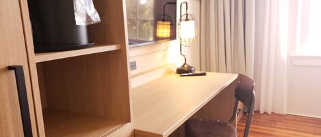 Ein Holztisch mit Stuhl, einer Lampe und einem Regal mit einem schwarzen Gegenstand.
