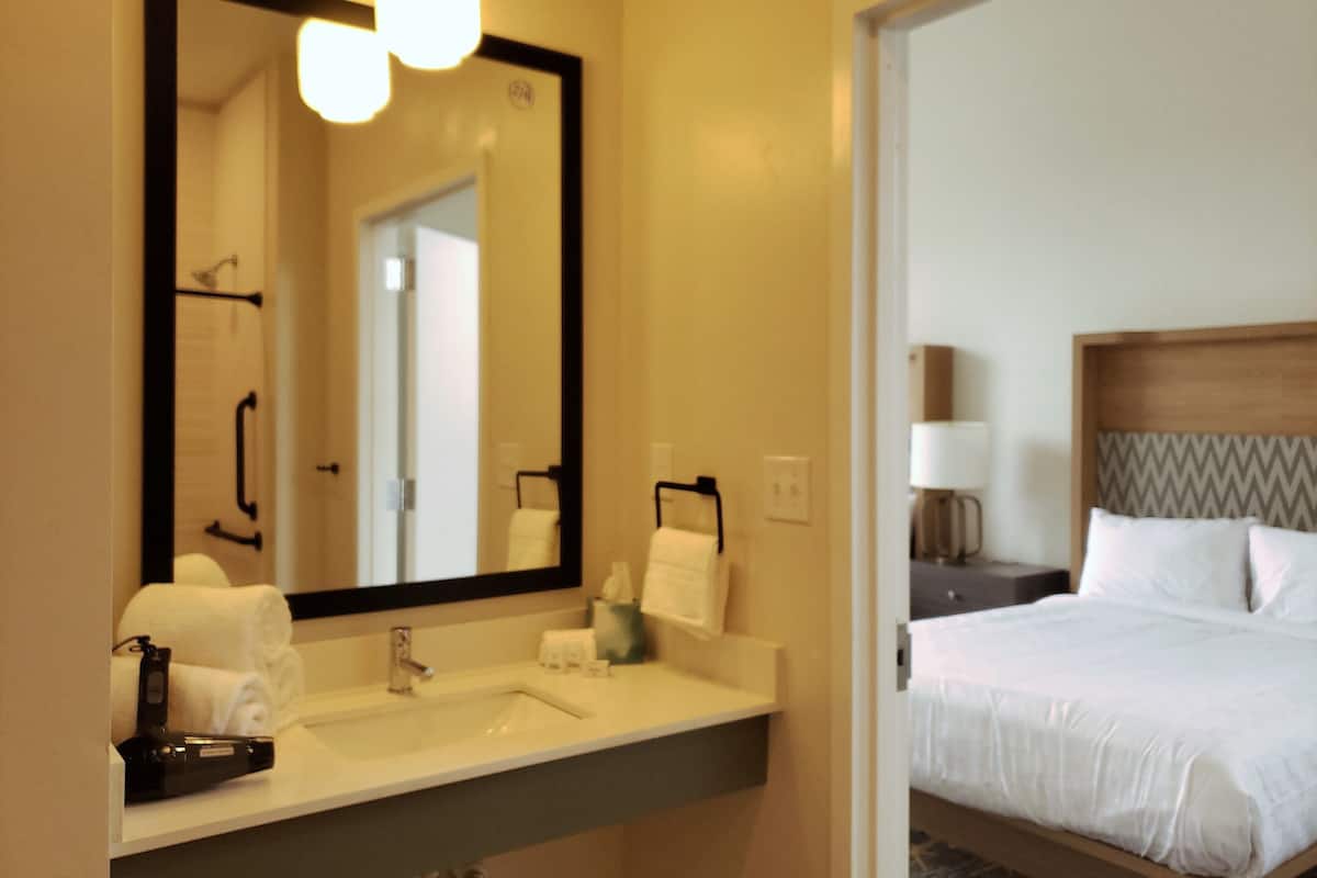 Um banheiro de hotel com um espelho grande, pia e porta-toalhas.