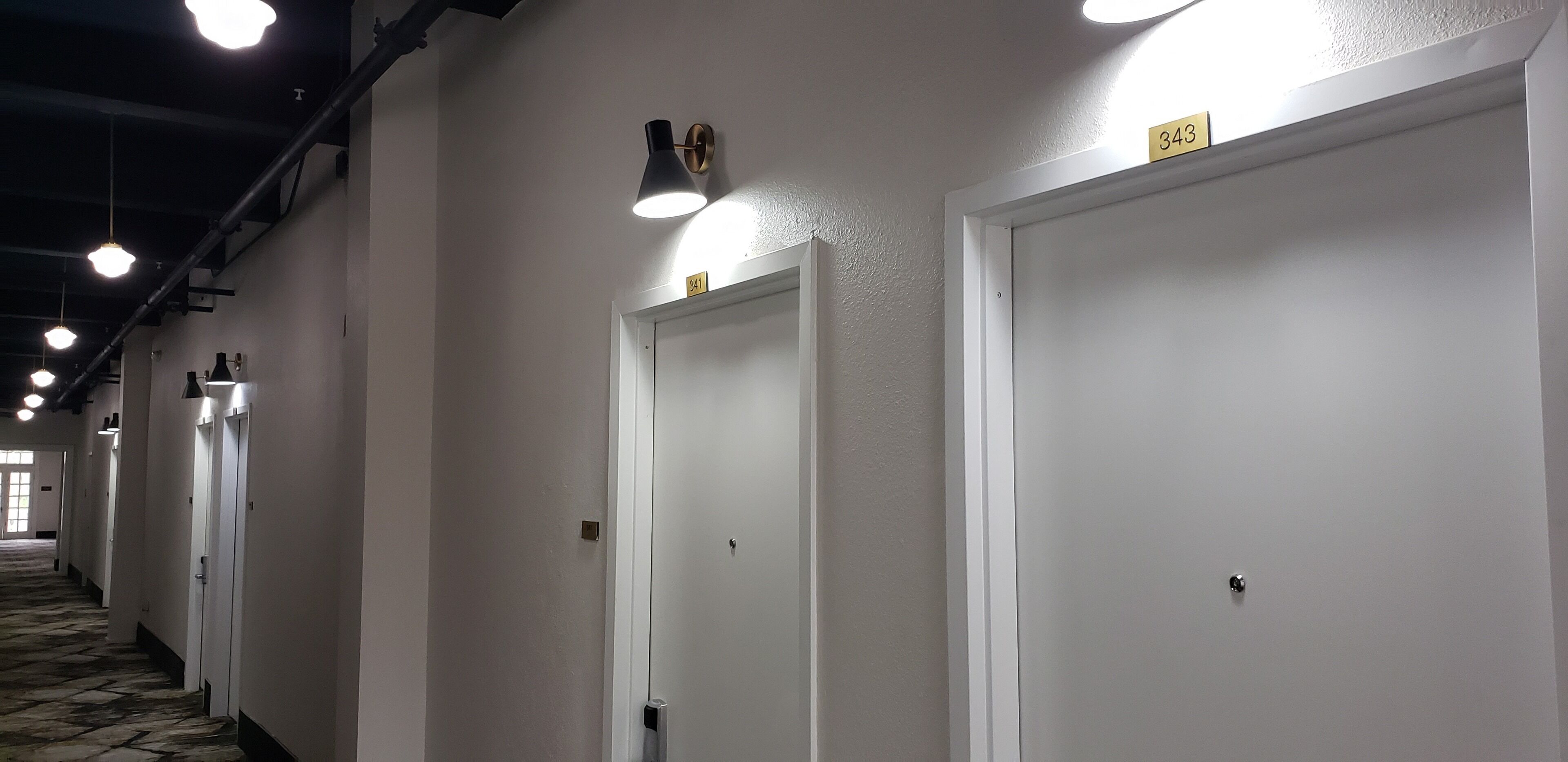 A hallway with white doors, each marked with a number.