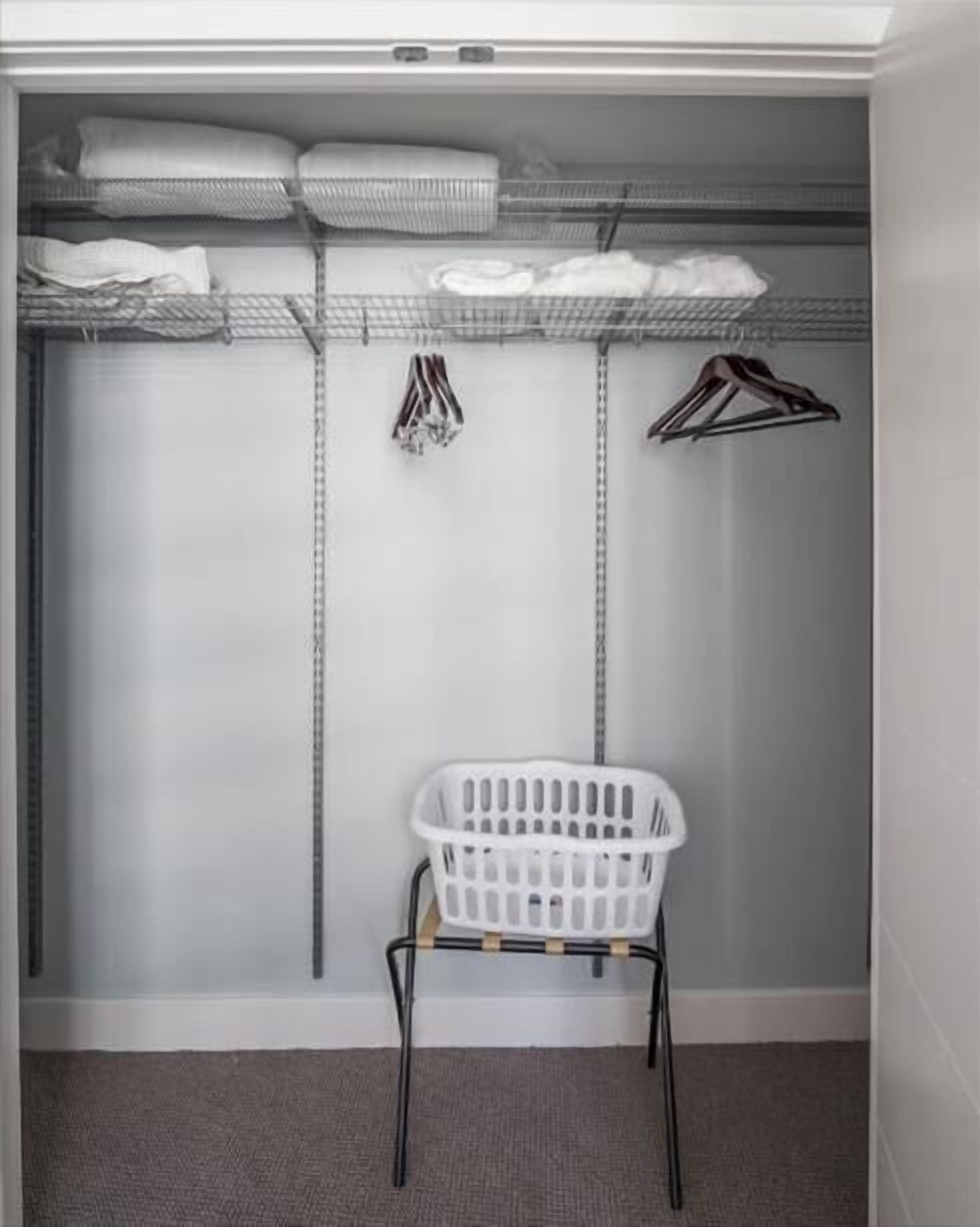 Un placard de rangement avec des étagères, une tringle et un panier à linge.
