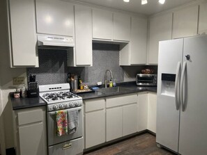 Eine moderne Küche mit weißen Schränken, einem Gasherd, einem Kühlschrank und einer Mikrowelle.