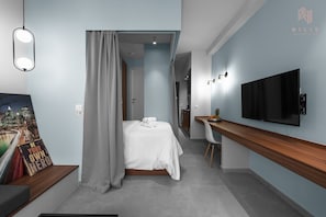 A modern hotel room with a bed, a desk, a TV, and a painting on the wall. - Big Apple 4 Nilie Hospitality MGMT (Thessaloniki)